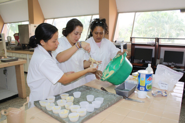 Volunteer Eliana Pinilla demonstrates sorghum processing techniques